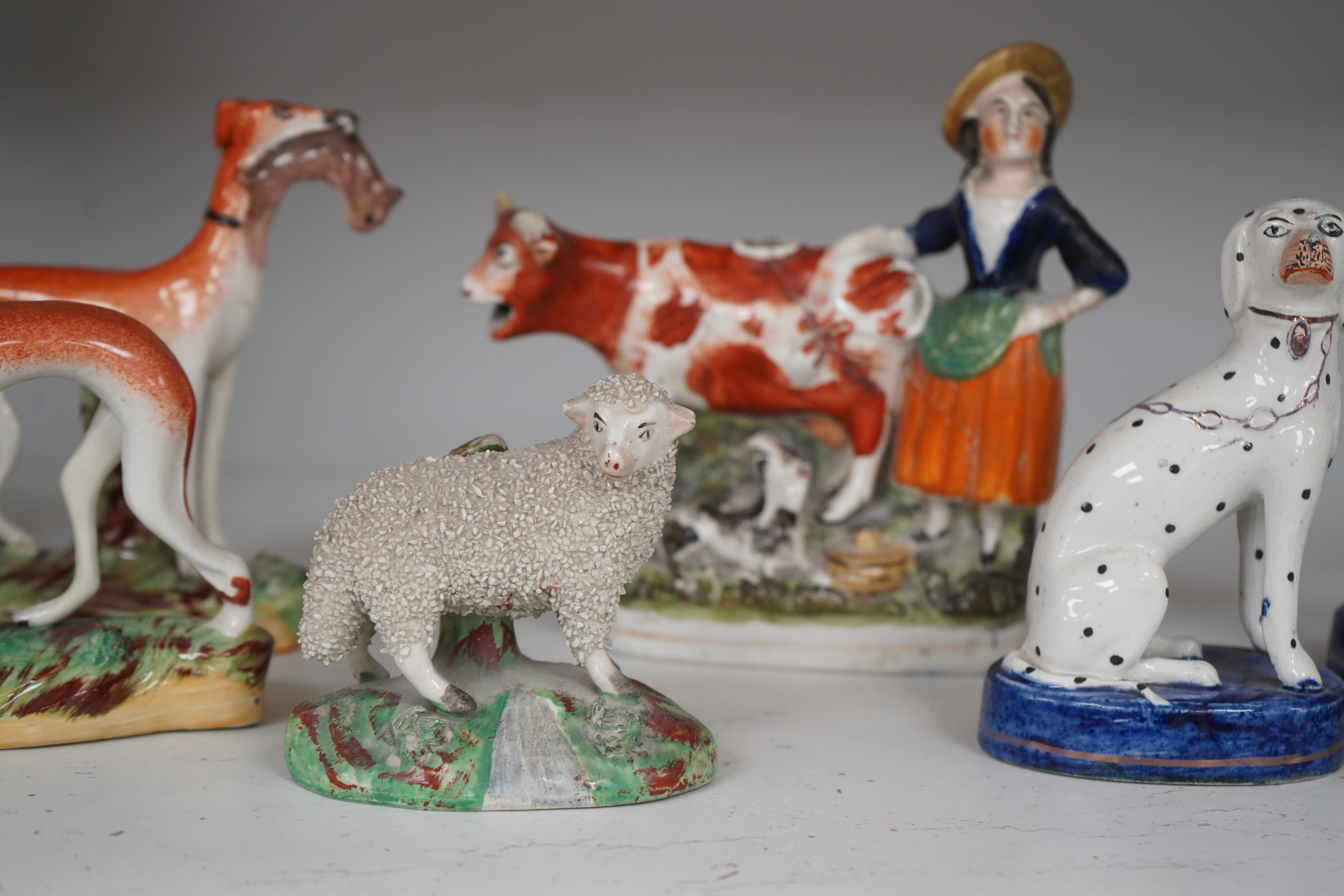 Eight Staffordshire figures to include a pair of Dalmatian’s and a cow creamer figure, largest 18cm wide. Condition - varies, poor to good